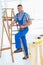 Carpenter with power drill climbing ladder at construction site