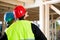 Carpenter In Protective Wear Standing By Colleague