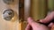 Carpenter repairing door lock. Installing a door handle. Handyman tightening door hinge . Hands of the repairman with a