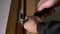 Carpenter repairing door lock. Installing a door handle. Handyman tightening door hinge . Hands of the repairman with a