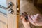 Carpenter repairing door lock. Installing a door handle. Handyman tightening door hinge . Hands of the repairman with a