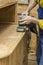 Carpenter restores vintage a sideboard by an electric of the grinding machine.