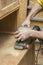 Carpenter restores vintage a sideboard by an electric of the grinding machine.