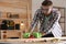 Carpenter shaping wooden bar with hand plane at table in workshop