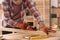 Carpenter shaping wooden bar with hand plane at table in workshop, closeup