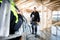 Carpenter Smiling While Female Colleague Carrying Ladder At Site