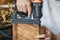 carpenter using nail gun or brad nailer tool on wood box in a workshop ,furniture restoration woodworking concept. selective focus