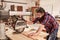 Carpenter using radial arm saw to cut wood in workshop