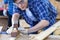 A carpenter is using a wood sharpener. Carpenter using back planer shavings manually on wooden board