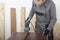 Carpenter working with  electric sheet finishing sander  on wood lath on desk, on background oriented strand board