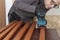 Carpenter working with electric sheet finishing sander on wooden  slats for production of  wooden garden bench on table in