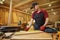 Carpenter working with a wood, marking plank with a pencil and taking measurements to cut a piece of wood to make a piece of