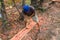 Carpenter works with hand tool a tree trunk. Worker on island of Bali sculpts a trough in a wooden beam. Heavy manual job