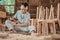 Carpenters sit while using chisels to carve wood