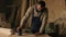 A carpentry shop with wood material, tools on the background. Joiner working on the processing of wood in blue overalls