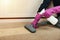 Carpet cleaning concept. cleaner`s hand in gloves sprays cleaning agent on the carpet and vacuums it.