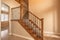 Carpeted stairs with wood handrail and metal railing inside an empty new home