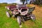 An carriage made of wood with large wheels without a horse on a mountainside on green grass. Retro and vintage from the story