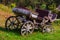 An carriage made of wood with large wheels without a horse on a mountainside on green grass. Retro and vintage from the story