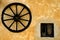 Carriage wheel hanged on a orange wall
