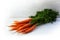 Carrot bunch with green leaves on bright wood with copy space, c