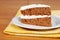 Carrot cake on a plate with yellow napkin