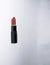 Carrot-colored vertical lipstick lies on a white background open without a cap in a black case