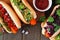 Carrot hot dogs with assorted toppings, close up on a wood background