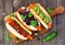 Carrot hot dogs with assorted toppings, top view on paddle board with a wood background