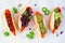 Carrot hot dogs with assorted toppings, top view on a white marble background