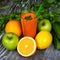 Carrot juice and multicolored fruit on wooden background