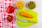 Carrot, knife on cutting board, green peas and corn in bowls, sweet peppers on napkin on table. Top view