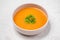 Carrot soup with cream and parsley on white stone background. To