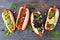 Carrot vegan hot dogs with assorted toppings, above view on a slate background