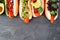 Carrot vegan hot dogs with assorted toppings, above view top border over a slate background