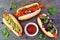 Carrot vegan hot dogs with assorted toppings, top view on a slate background