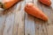 Carrot whole and in the peel lies on a wooden table