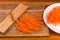 Carrots chopped into thin long slices on dish and grater