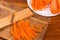 Carrots chopped into thin long slices on dish and grater