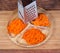 Carrots grated in different ways with kitchen grater on wooden dish