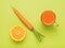 Carrots, half an orange and a glass of smoothies on a green background. Flat lay