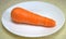 Carrots. One. Whole for cooking different dishes. On a white plate. Vegetables. Food.