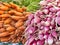 Carrots and radishes in piles on a retail display.