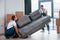 Carrying heavy sofa. Two young movers in blue uniform working indoors in the room