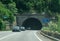 Cars come out of the road tunnel. Road traffic on a street that crosses the mountains.