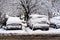 Cars covered with snow from the first snow fall of the year. Winter concept, snowy cars parked on the street, deep layer of snow