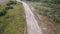 Cars are crossing narrow dirt dusty road. Motion toward. High angle view.