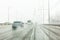 Cars drive along road with slush, snowstorm. City traffic in snow blizzard