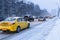 Cars drive on snowy city road in blue winter dusk