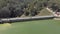 Cars driving across barrage dam, Munnar, India. Aerial backward